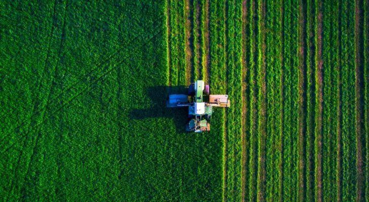 a tractor cultivating a farm from an aerial view
