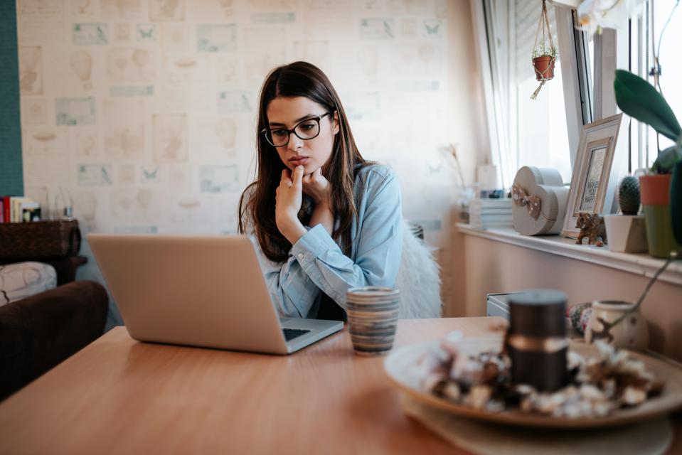 Worried girl looking at laptop screen at home.