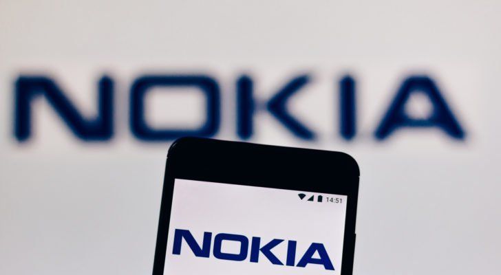 a backdrop featuring the Nokia (NOK) logo with a mobile phone featuring the Nokia logo on its screen in the foreground