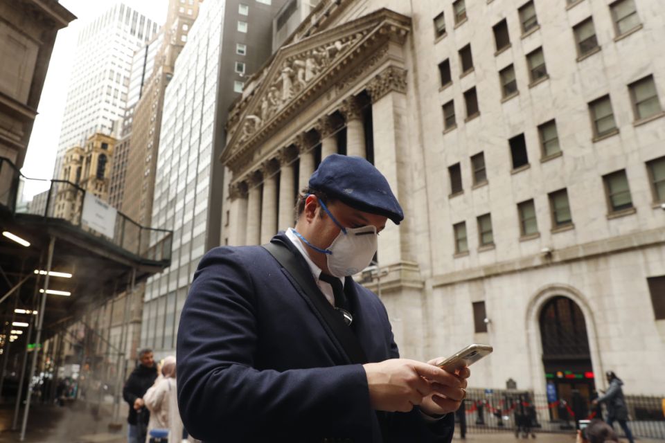 A man wears a protective mask as he walks past the New York Stock Exchange on the corner of Wall and Broad streets during the coronavirus outbreak in New York City, New York, U.S., March 13, 2020. REUTERS/Lucas Jackson