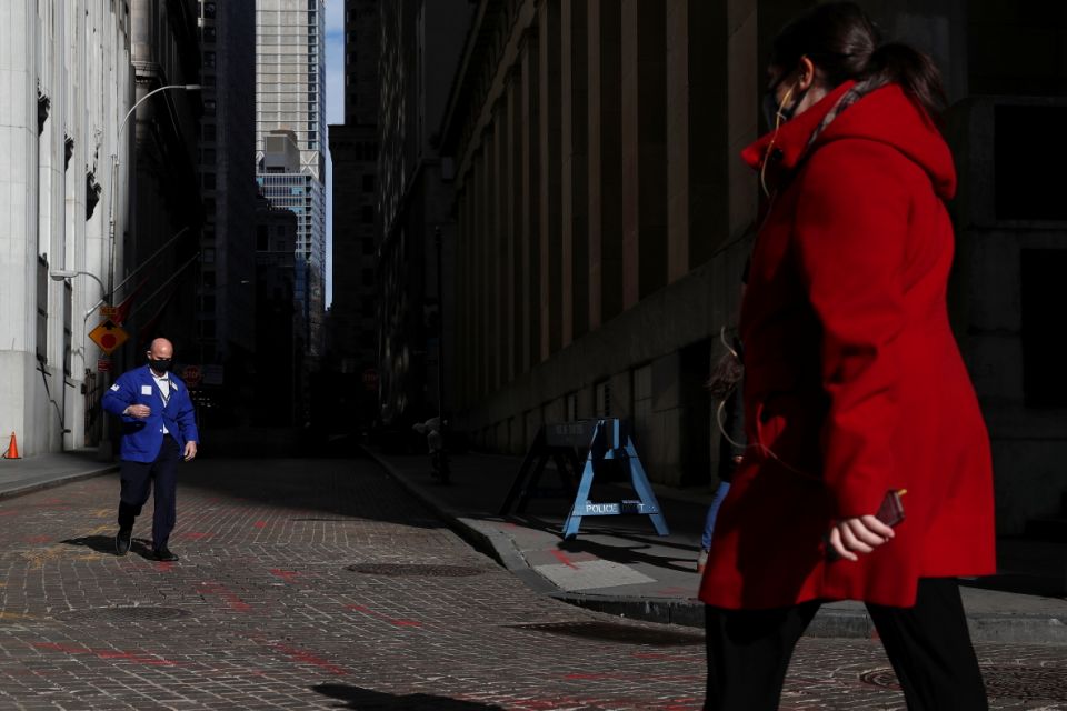 A trader wearing a protective face mask walks, as the global outbreak of the coronavirus disease (COVID-19) continues, outside the New York Stock Exchange (NYSE)  in the financial district of New York, U.S., November 19, 2020. REUTERS/Shannon Stapleton