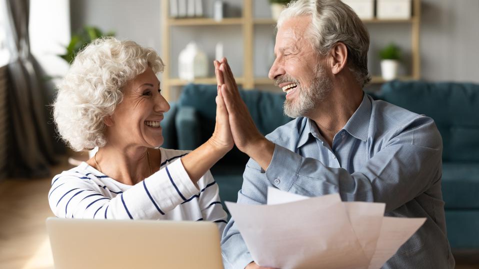 Excited older couple giving high five, celebrating good news