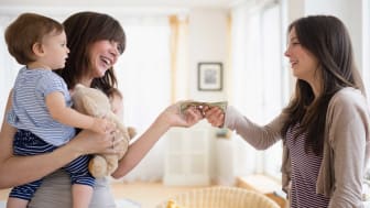 picture of a mother holding a child and paying a nanny