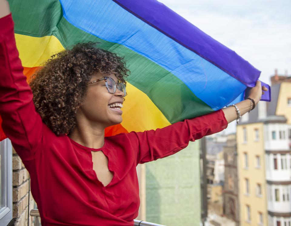 Young lady waving a gay pride flag in support of Gay Pride