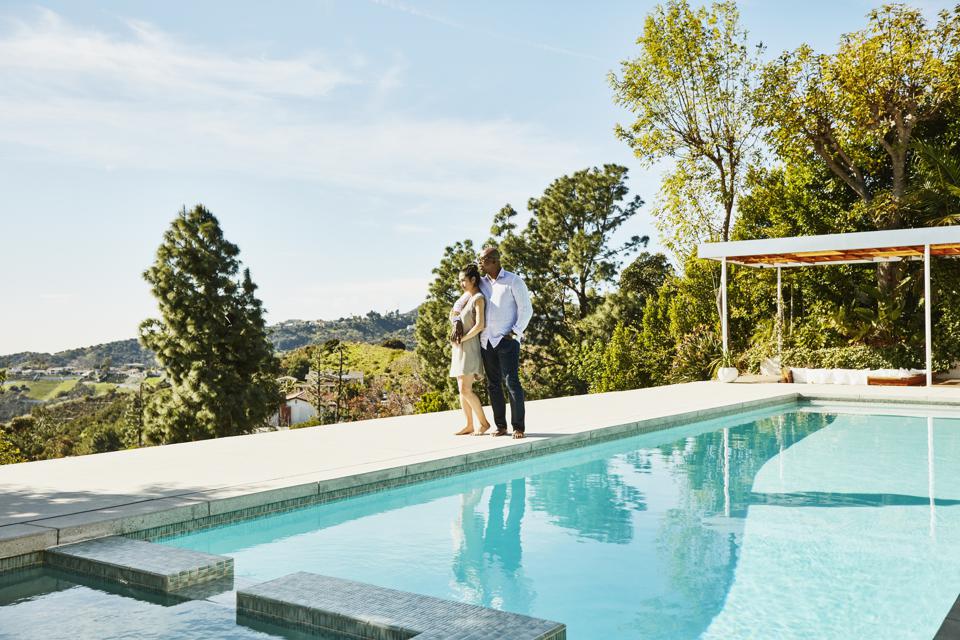 Embracing couple standing next to pool and admiring view