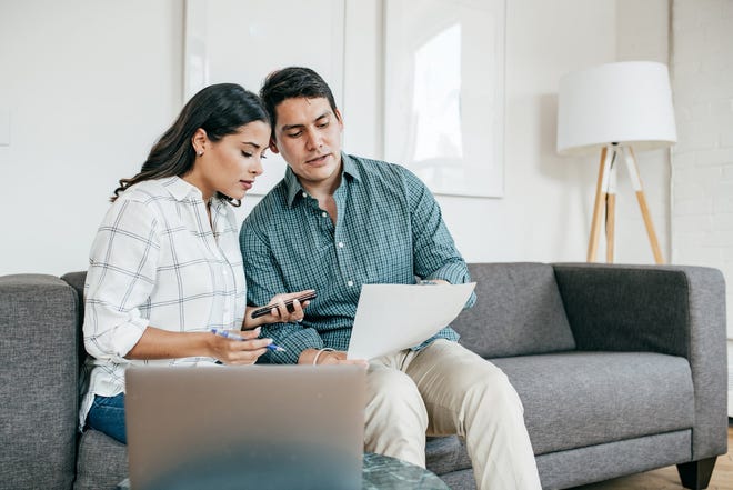 Two people sitting on a couch looking at documents