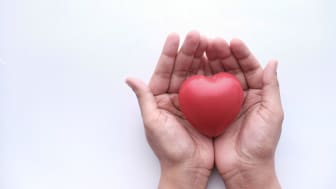 Photo illustration of two hands cupping a heart symbolizing charity