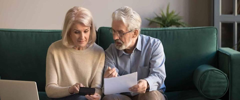 Serious mature couple calculating bills to pay, checking domestic finances.